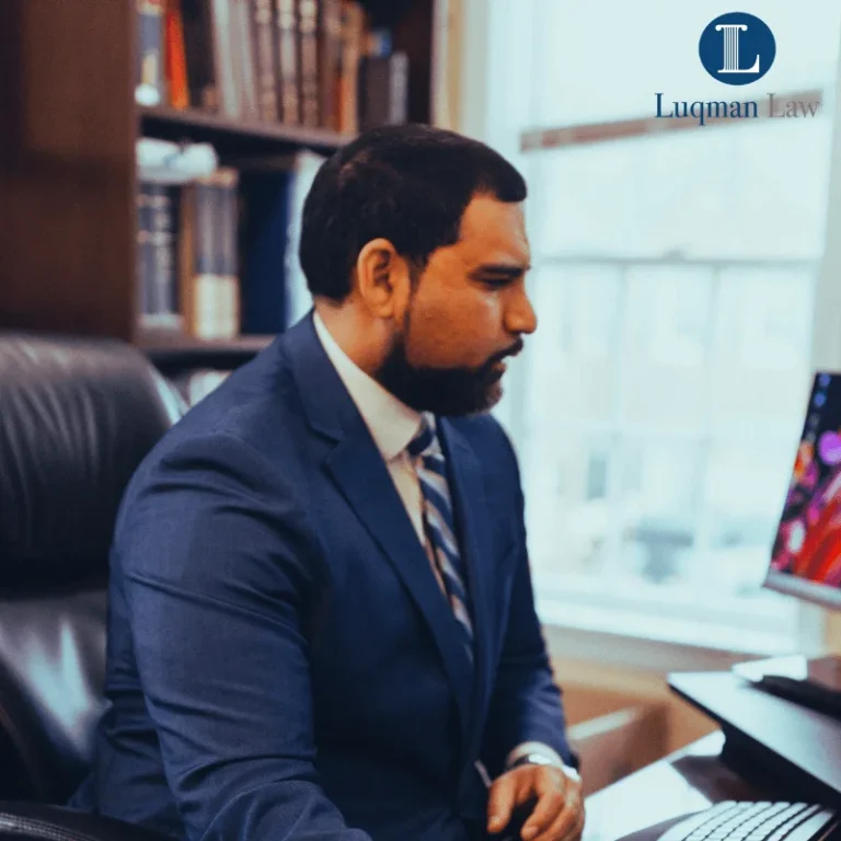 A professional man in a blue suit and a striped tie working attentively on a laptop at a desk in an office setting, with a text overlay reading "WORK PERMITS EXTENDED 540 DAYS" at the bottom and a logo that reads "Lugman Law" at the top right.