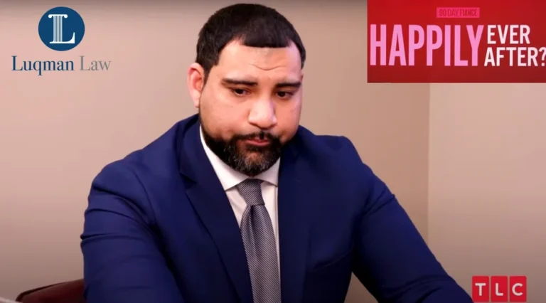 Man in a blue suit looking down with a serious expression, standing in front of a background with a red "HAP" logo.