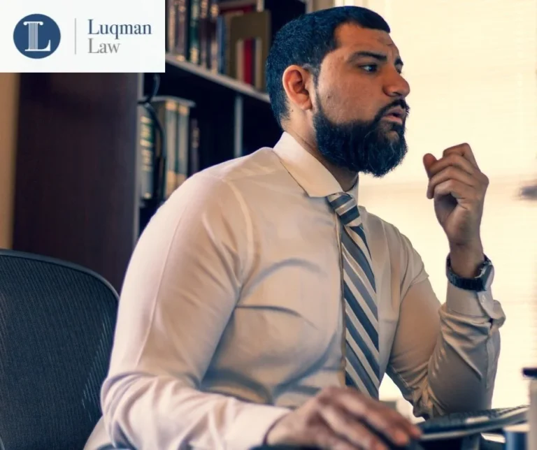 A bearded man in a light beige shirt and striped tie holding a smartphone, deep in thought, sitting by a shelf with books, with a 'Langman Law' logo in the top left corner.